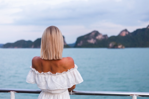 Romantic portrait of woman in white dress sailing on large boat ferry