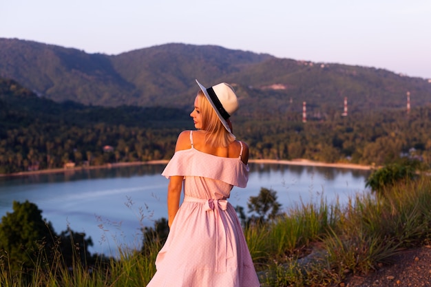 Free Photo romantic portrait of young caucasian woman in summer dress enjoying relaxing in park on mountain with amazing tropical sea view female on vacation travel around thailand happy woman at sunset