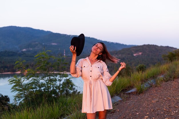 Romantic portrait of young caucasian woman in summer dress enjoying relaxing in park on mountain with amazing tropical sea view