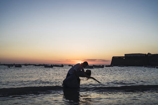 Free Photo romantic shot of a couple's silhouette on the beach captured in the sunset