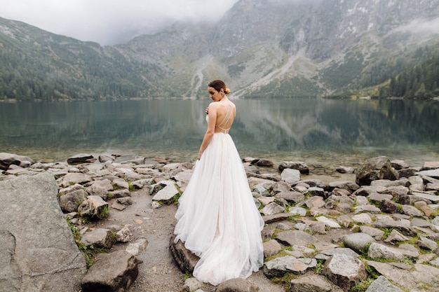 Free Photo romantic wedding couple in love standing of the sea eye lake in poland. tatra mountains.