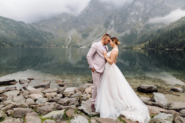 Free Photo romantic wedding couple in love standing of the sea eye lake in poland. tatra mountains.