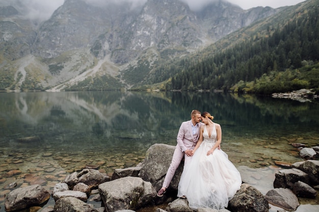 Free Photo romantic wedding couple in love standing of the sea eye lake in poland. tatra mountains.