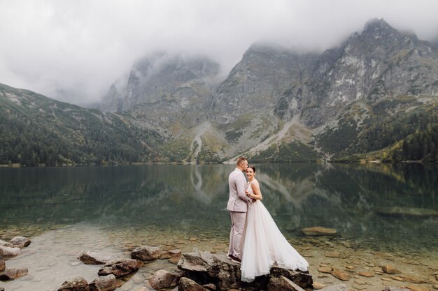 Romantic wedding couple in love standing of the Sea Eye lake in Poland. Tatra mountains.