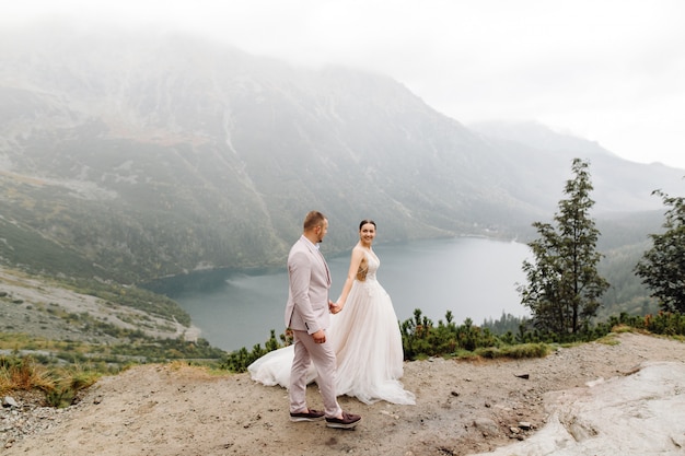 Romantic wedding couple in love standing of the Sea Eye lake in Poland. Tatra mountains.