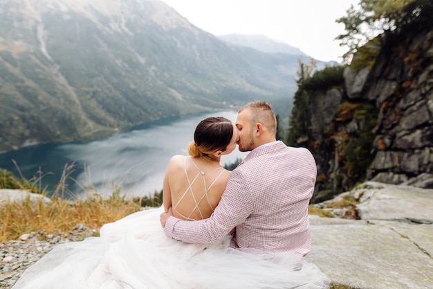 Free Photo romantic wedding couple in love standing of the sea eye lake in poland. tatra mountains.