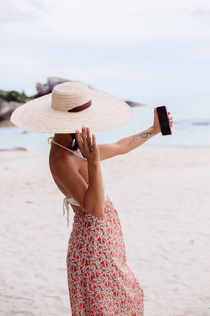 Romantic woman on beach in skirt knitted top and straw hat