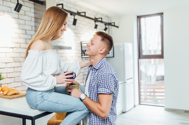 Romantic young couple drinking coffee together in the kitchen, having a great time together.