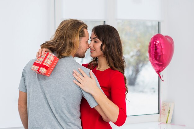 Romantic young couple embracing each other in front of window