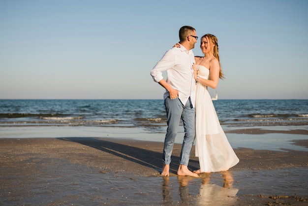 Free Photo romantic young couple looking at each other standing near the sea at beach