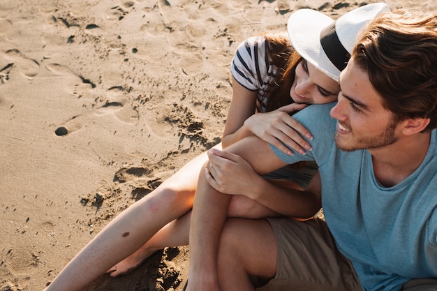 Free photo romantic young couple sitting next to the sea