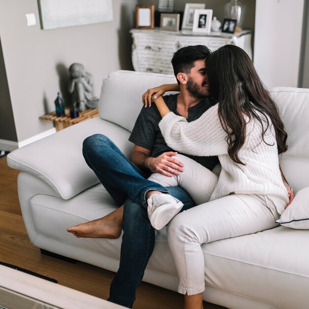 Romantic young couple sitting on white sofa loving each other