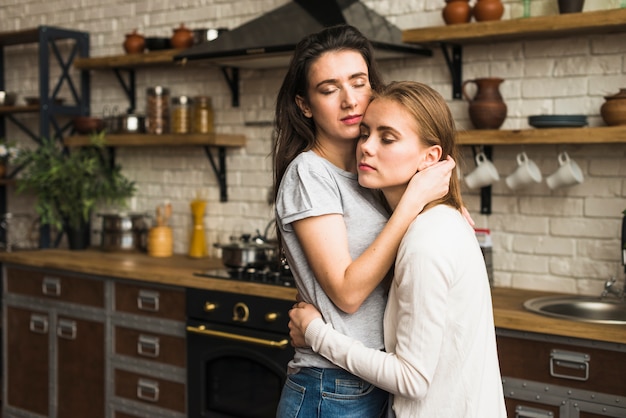 Romantic young lesbian couple standing in the kitchen