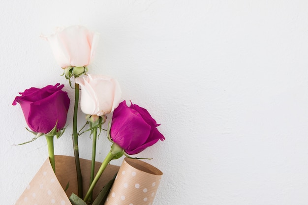 Rose flowers in package paper on white table