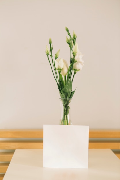 Free photo rose flowers in vase with blank paper