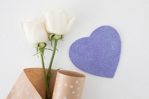 Rose flowers with paper heart on table