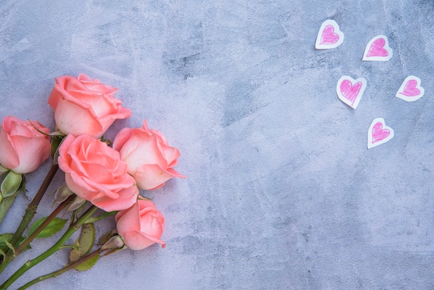 Free photo rose flowers with paper hearts on table