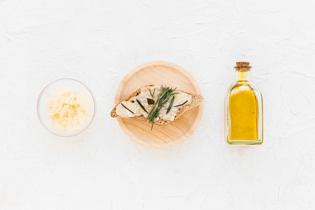 Free Photo rosemary and cheese on bread with oil bottle on white backdrop