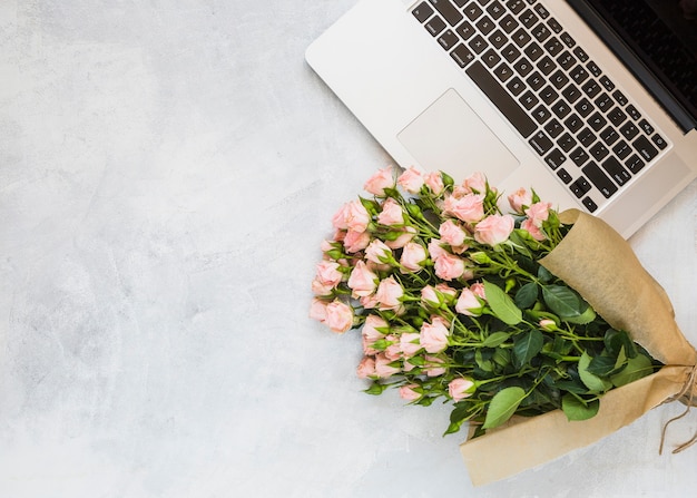 Roses bouquet with an open laptop on concrete background