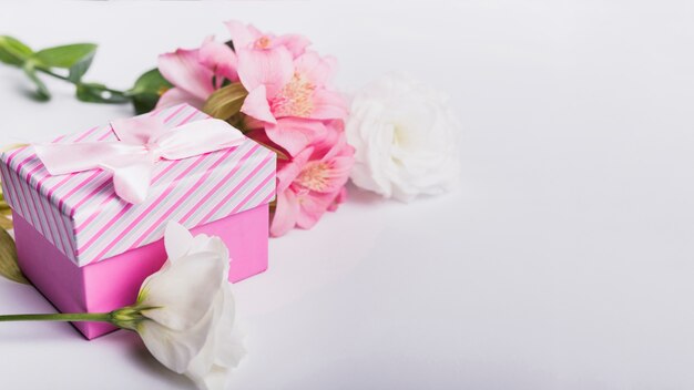 Roses and pink lily flowers with gift box on white background