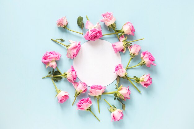 Roses surrounding blank circular frame on blue backdrop