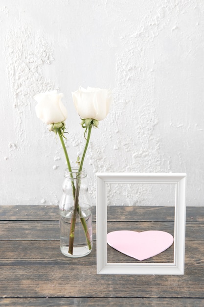 Free photo roses in vase with frame and paper heart