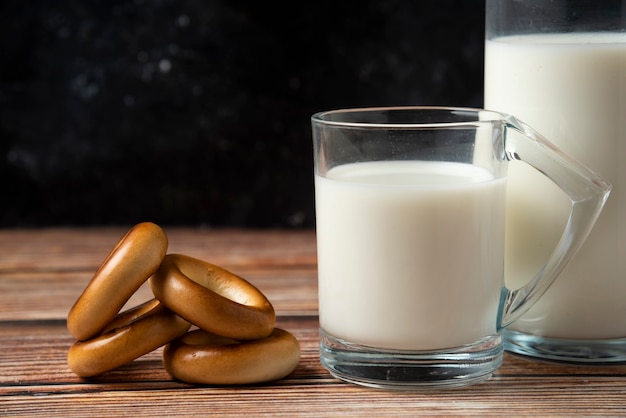 Free photo round biscuits, a bottle of milk and a glass of milk on wooden table.