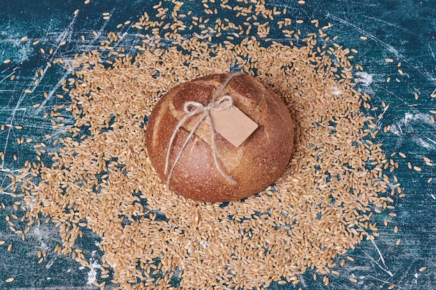 Round bread with wheats on blue table.