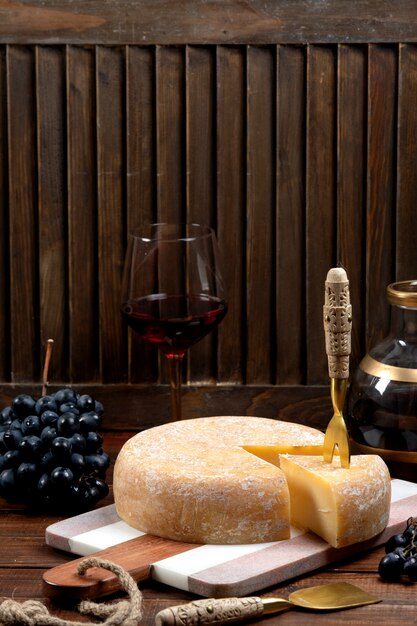 Round cheddar cheese and a slice on marble board