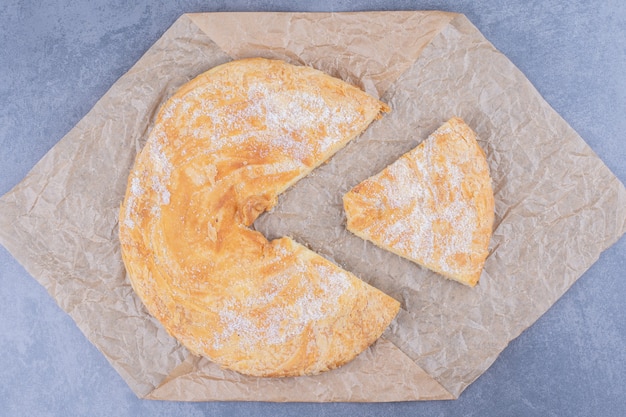 Free photo a round delicious pastry with sugar powder on a tablecloth