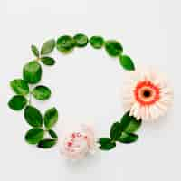 Free photo round frame made of peony and gerbera flowers with green leaves