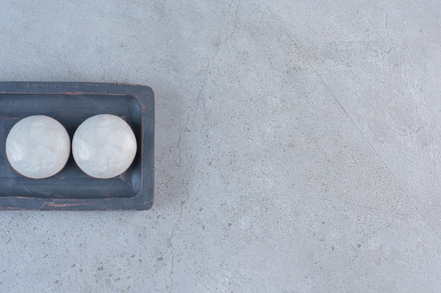 Round glazed biscuits on black plate on stone table.