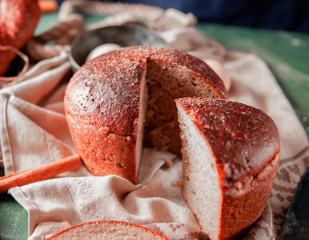 Round healthy bread sliced on a white tablecloth with cinnamon around. 