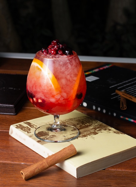 Free photo a round-shaped glass with berry cocktail with orange slices