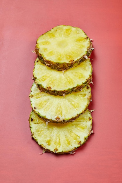 Round slices of pineapple on pink table.