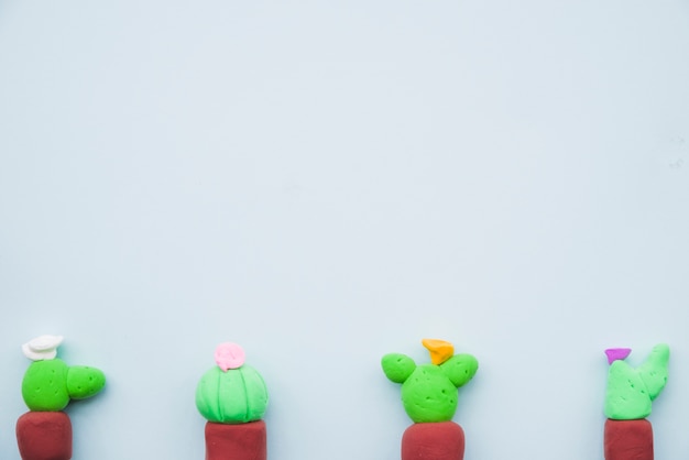 Free Photo row of colorful cactus made with clay on gray background