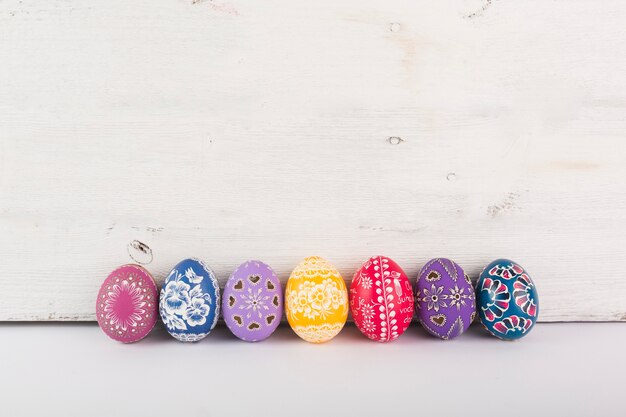 Row of colorful eggs on wood