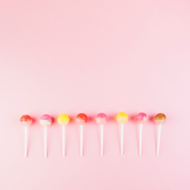 Row of colorful lollipops on pink background