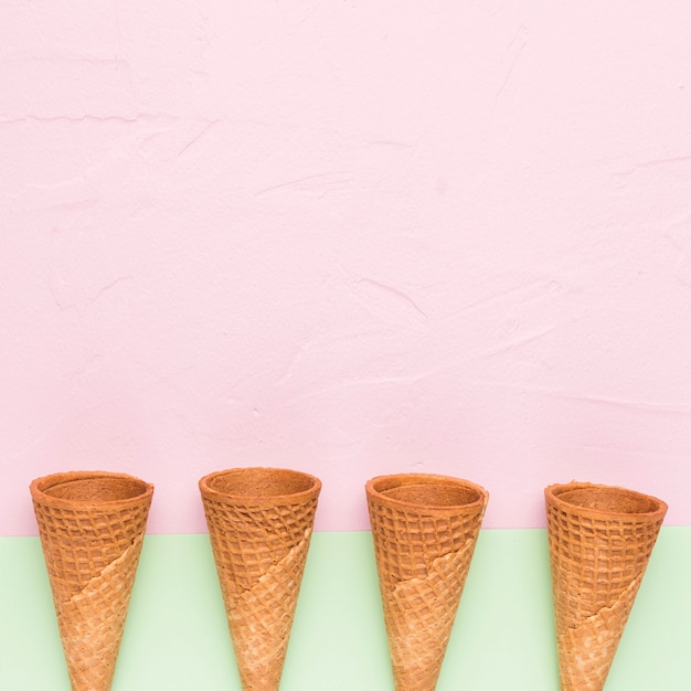 Row of empty ice cream cones on multicolored surface