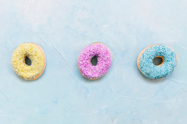 Free Photo row of fresh multi colored donuts on blue background