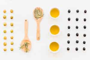 Free photo row of green and black olive with oil and herbs on plain background