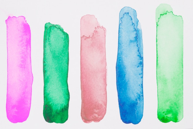 Row of green, pink and blue paints on white paper