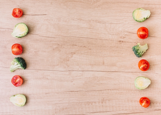 Free photo row of halved cherry tomatoes; brussel sprouts; broccoli on wooden desk with copy space for writing the text