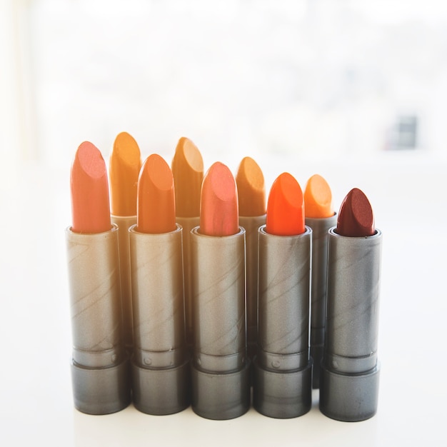 Row of lipsticks in different shades on white background