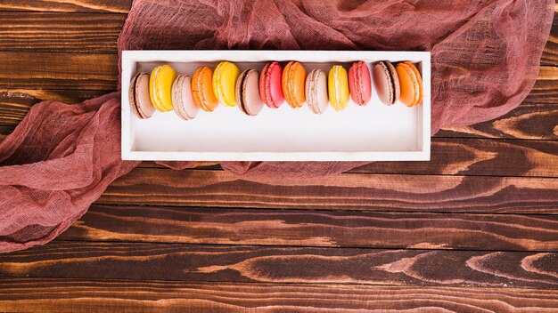 Row of macaroon in the white wooden box over the table