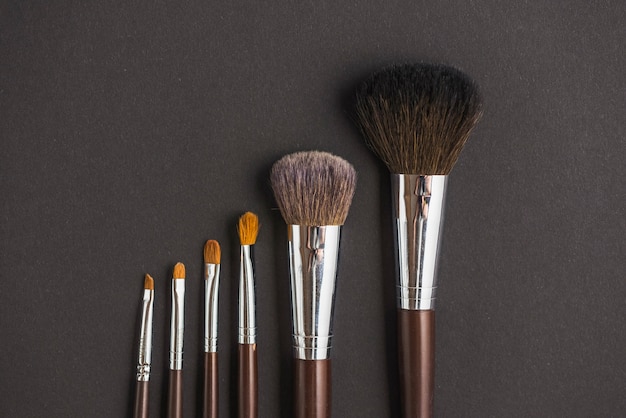 Free photo row of makeup brushes on black backdrop