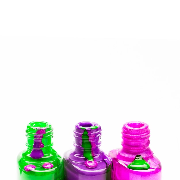 Row of open colored nail polish bottle on white background