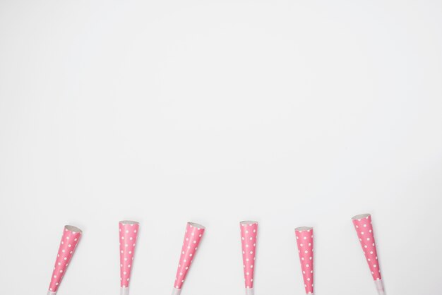 Row of pink party horn blowers on white background