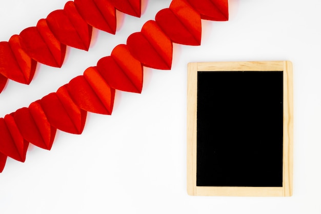 Rows of ornament red hearts near photo frame 