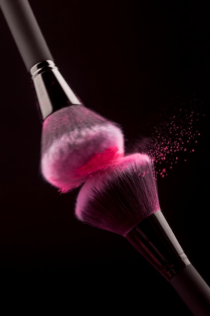 Free photo rubbing professional makeup brushes with pink powder